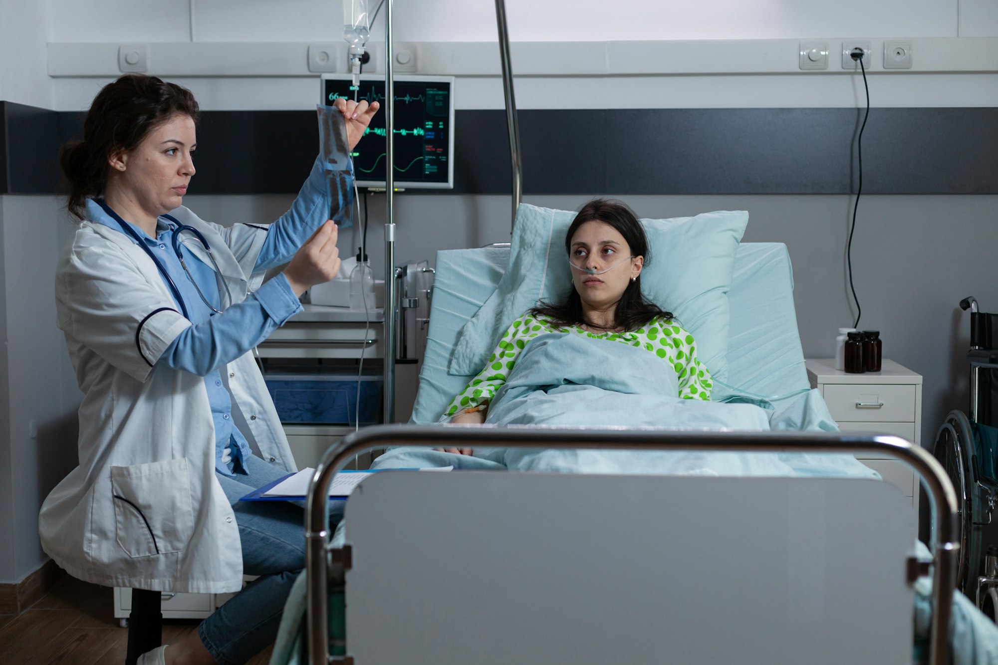 Medical doctor at patient bedside looking at pulmonary radiography