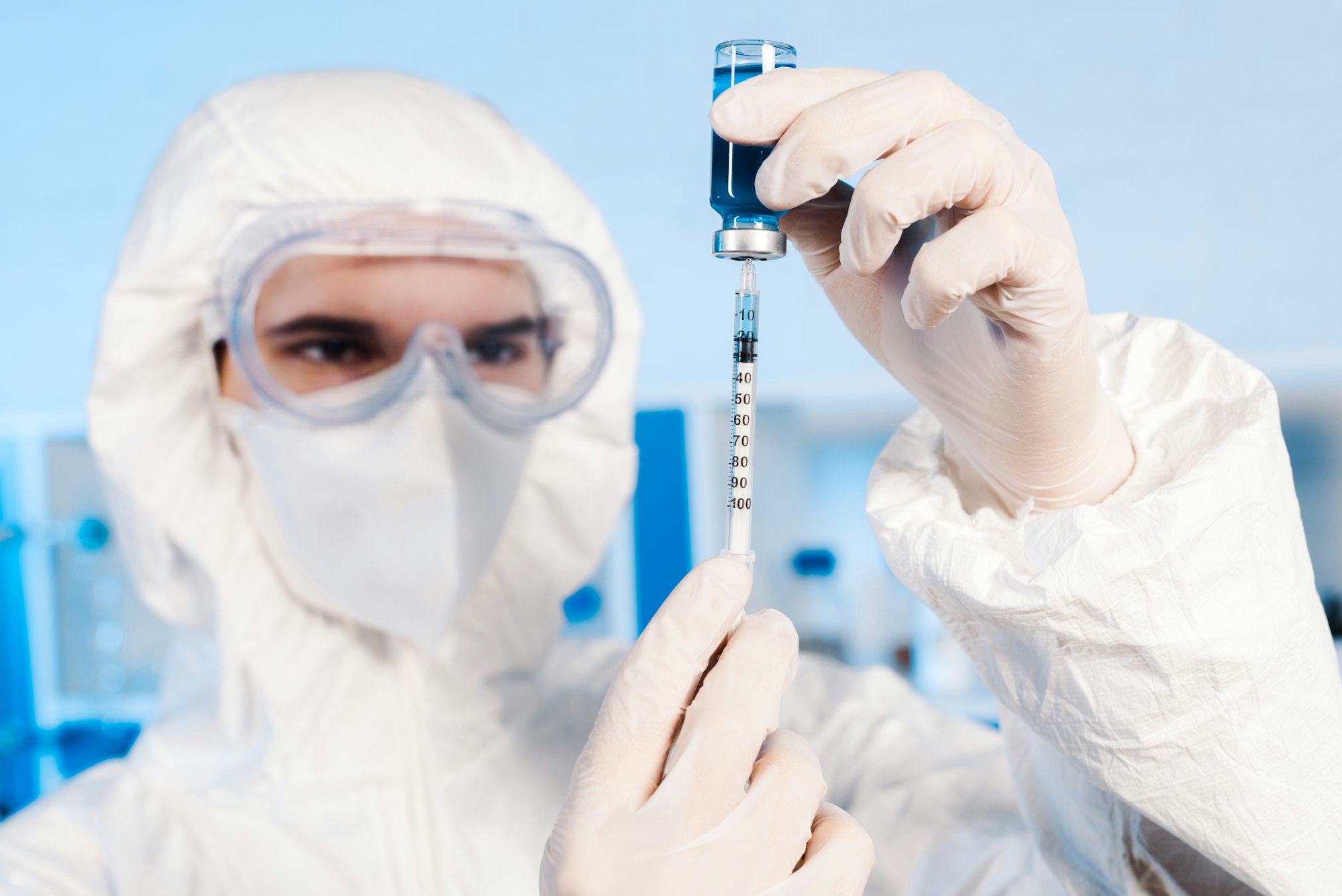 selective focus of scientist holding syringe and bottle with vaccine